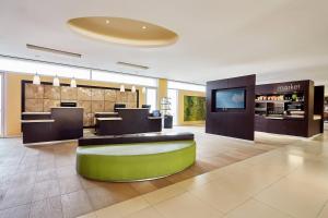 a lobby of a hotel with a green bench and tables at Courtyard by Marriott Leon at The Poliforum in León
