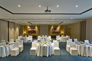 uma sala de banquetes com mesas brancas e cadeiras brancas em Fairfield by Marriott Coimbatore em Coimbatore