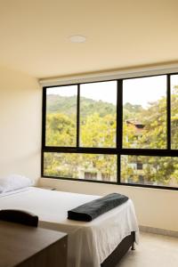 a bedroom with a bed and a large window at Hotel Brisas del Nus in San Roque