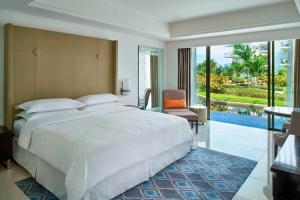 a bedroom with a large white bed and a balcony at Sheraton Bali Kuta Resort in Kuta