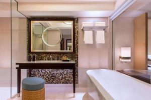 a bathroom with a tub and a sink and a mirror at Sheraton Bali Kuta Resort in Kuta