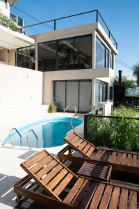 2 sillas de madera sentadas junto a una piscina en Altos Apart Carlos Paz en Villa Carlos Paz