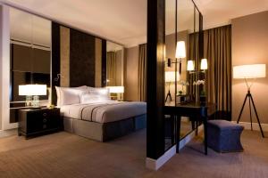 a bedroom with a bed and a desk and a mirror at The Ritz-Carlton, Kuala Lumpur in Kuala Lumpur