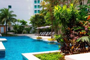 a pool in a hotel with chairs and palm trees at The Ritz-Carlton, Kuala Lumpur - TravelEase Visa-Free Getaway in Kuala Lumpur
