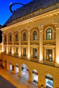 duży ceglany budynek z łukiem w nocy w obiekcie Millennium Court, Budapest - Marriott Executive Apartments w Budapeszcie