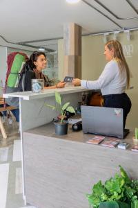 Due donne in piedi ad una scrivania in un ufficio di Ventiuna Hotel y Coliving a Pereira