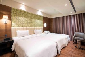 sypialnia z dużym białym łóżkiem i krzesłem w obiekcie The Cloud Hotel w mieście Taizhong