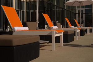 eine Reihe von Tischen mit orangefarbenen Stühlen und Sonnenschirmen in der Unterkunft Aloft Corpus Christi in Corpus Christi