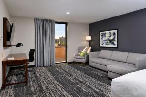 Habitación de hotel con sofá, cama y escritorio. en Four Points by Sheraton Omaha Midtown, en Omaha