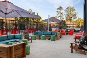 a patio with couches and chairs and umbrellas at Aloft Houston Shenandoah - The Woodlands in Shenandoah