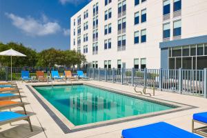 einen Pool mit Stühlen und ein Gebäude in der Unterkunft Aloft San Antonio Airport in San Antonio