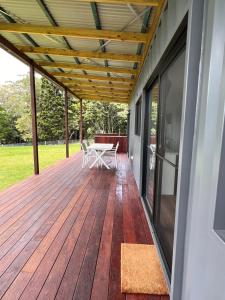 a wooden deck with a table and chairs on it at Three Pines House - Unique Tiny House with Views in Mount Tamborine