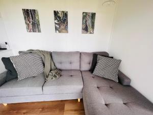 a living room with a gray couch with two pillows at Three Pines House - Unique Tiny House with Views in Mount Tamborine