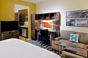 a hotel room with a bed and a desk and a kitchen at TownePlace Suites by Marriott Anchorage Midtown in Anchorage