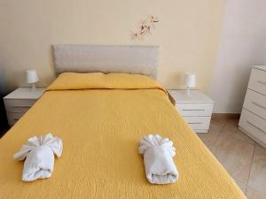 een slaapkamer met een geel bed en handdoeken bij Casa Ortigia in Siracusa