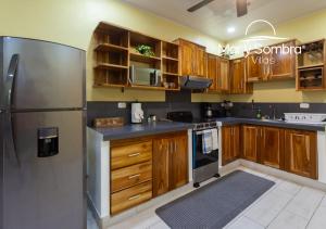 a kitchen with wooden cabinets and a stainless steel refrigerator at Mar y Sombra Villas in Quepos