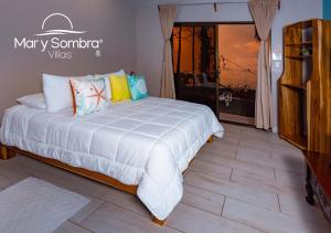 a bedroom with a large white bed with pillows at Mar y Sombra Villas in Quepos