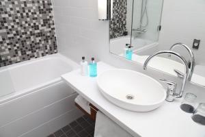 a white bathroom with a sink and a bath tub at Hotel Katajanokka, Helsinki, a Tribute Portfolio Hotel in Helsinki