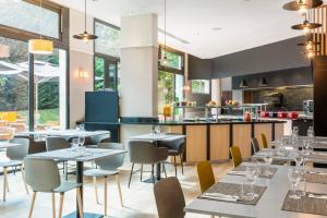 um restaurante com mesas e cadeiras e uma cozinha em Courtyard by Marriott Paris Saint Denis em Saint-Denis