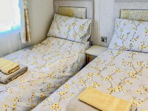 um quarto com duas camas com flores amarelas em Ballagan Lodge em Leanach