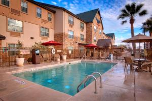 a pool in front of a hotel with tables and umbrellas at TownePlace Suites by Marriott Sierra Vista in Sierra Vista