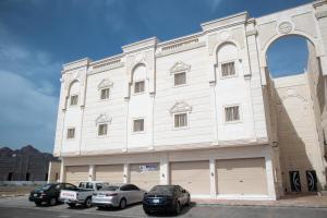 un edificio blanco con coches estacionados frente a él en Luxurious Family 3 Bedroom Apartments 10 Mins Drive to Al-Masjid Nabawi - Qaswarah residence, en Medina