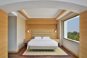 a bedroom with a bed and a large window at Courtyard by Marriott Chennai in Chennai