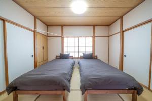dwa łóżka w pokoju z oknem w obiekcie コーポセキヤ / Corp Sekiya w mieście Itoigawa