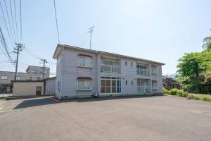 biały budynek z oknami i parkingiem w obiekcie コーポセキヤ / Corp Sekiya w mieście Itoigawa