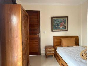 a bedroom with a bed and a wooden closet at Adipana Bungalow-Balinese Room in Ubud