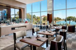 a restaurant with tables and chairs and large windows at AC Hotel by Marriott San Francisco Airport/Oyster Point Waterfront in South San Francisco