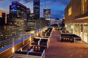 a rooftop patio with a view of the city at night at Le Meridien Houston Downtown in Houston