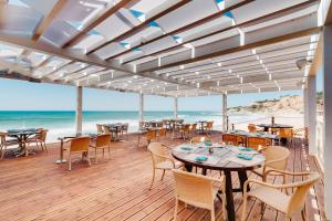 un restaurante en la playa con mesas y sillas en Pine Cliffs Ocean Suites, a Luxury Collection Resort & Spa, Algarve, en Albufeira