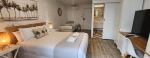 - une chambre avec un grand lit blanc et une télévision dans l'établissement Peninsula Beach Motel, à Rosebud