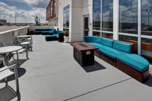 un patio all'ultimo piano con divano blu, tavoli e sedie di SpringHill Suites by Marriott Wichita Airport a Wichita