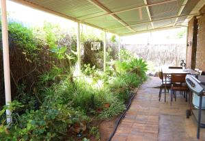 un patio con mesa, sillas y plantas en Capon Cottage, en Broken Hill