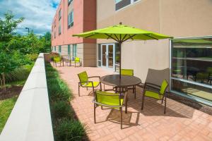 une terrasse avec une table, des chaises et un parasol dans l'établissement SpringHill Suites By Marriott Columbia Fort Meade Area, à Columbia