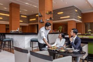 Courtyard by Marriott Bangkok في بانكوك: ثلاثة أشخاص يجلسون على طاولة في مطعم