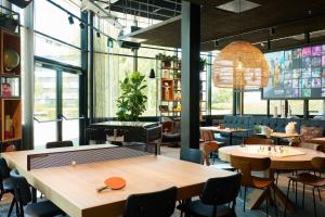 een restaurant met een tafeltennistafel en stoelen bij Moxy Amsterdam Schiphol Airport in Hoofddorp