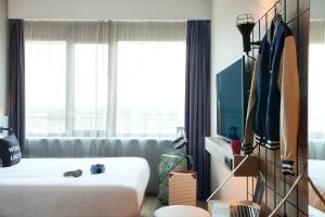 ein Schlafzimmer mit einem Bett und einem großen Fenster in der Unterkunft Moxy Amsterdam Schiphol Airport in Hoofddorp