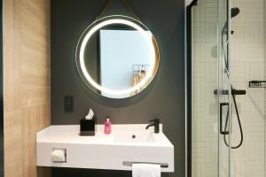 a bathroom with a white sink and a mirror at Moxy Amsterdam Schiphol Airport in Hoofddorp