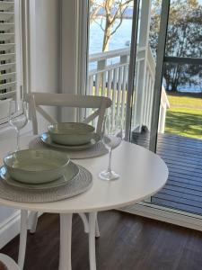 a white table with two plates and wine glasses on a porch at B & B On The Water in Sanctuary Point