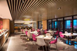 a restaurant with pink chairs and tables and windows at Aloft Taipei Beitou in Taipei