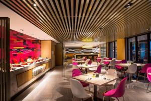 a restaurant with tables and chairs and pink chairs at Aloft Taipei Beitou in Taipei