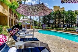 a pool with chairs and an umbrella next to a pool at Avenue of the Arts Costa Mesa, a Tribute Portfolio Hotel in Costa Mesa