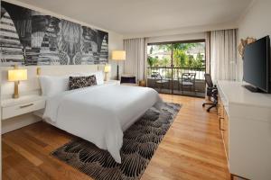 a bedroom with a large white bed and a flat screen tv at Avenue of the Arts Costa Mesa, a Tribute Portfolio Hotel in Costa Mesa