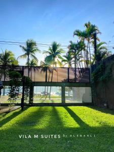 a house with palm trees on a grass field at Vila M Suítes ᵇʸ ᴬᴸᴱᴮᴬᴴᴸᴵ in Ilhabela