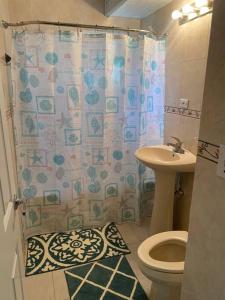a bathroom with a shower curtain and a toilet and a sink at Condo in the middle of Everything! in Nassau