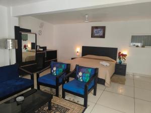 a bedroom with a bed and two blue chairs at Green Serene Abode in Meerut