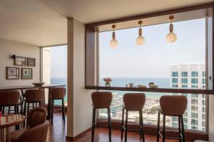 a restaurant with a bar with a view of the ocean at Renaissance Tel Aviv Hotel in Tel Aviv